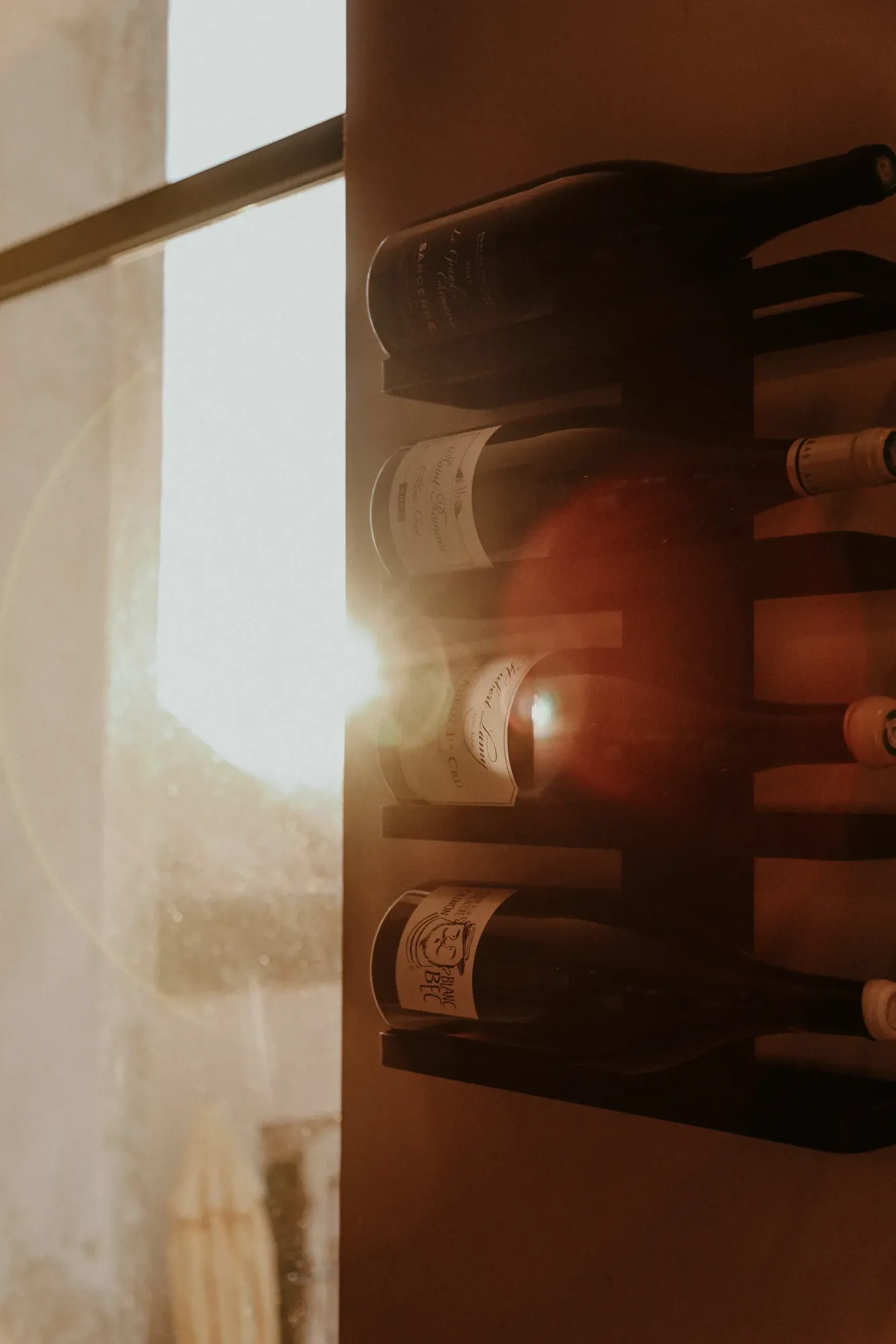 Des bouteilles de vin sur le mur de La Banque, dans la lumière de la fenêtre