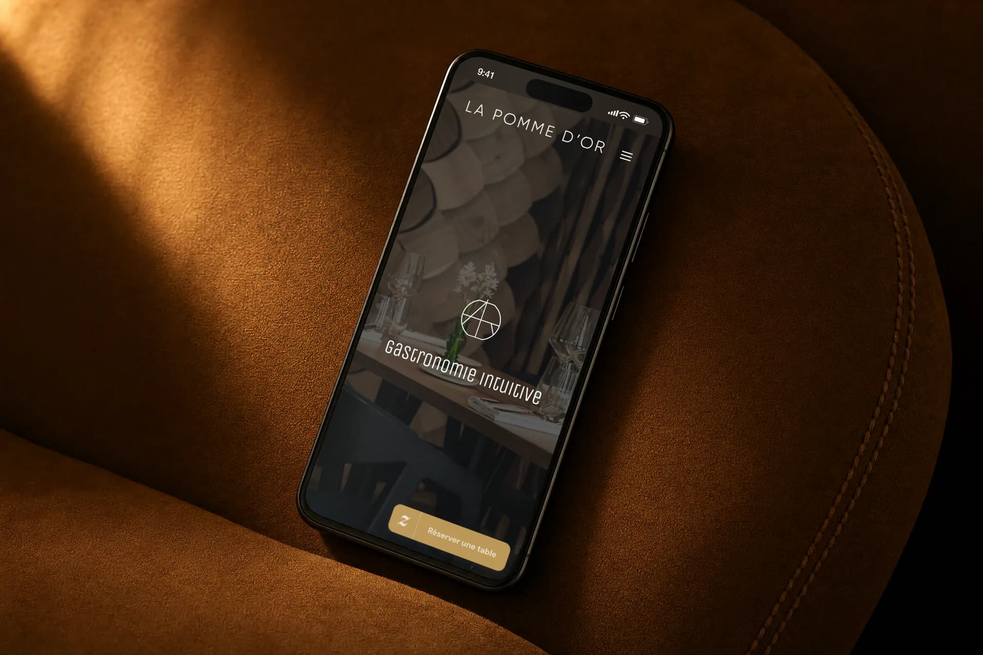 Le site internet de La pomme d'or, restaurant étoilé de Sancerre, sur un téléphone posé sur un fauteuil en daim