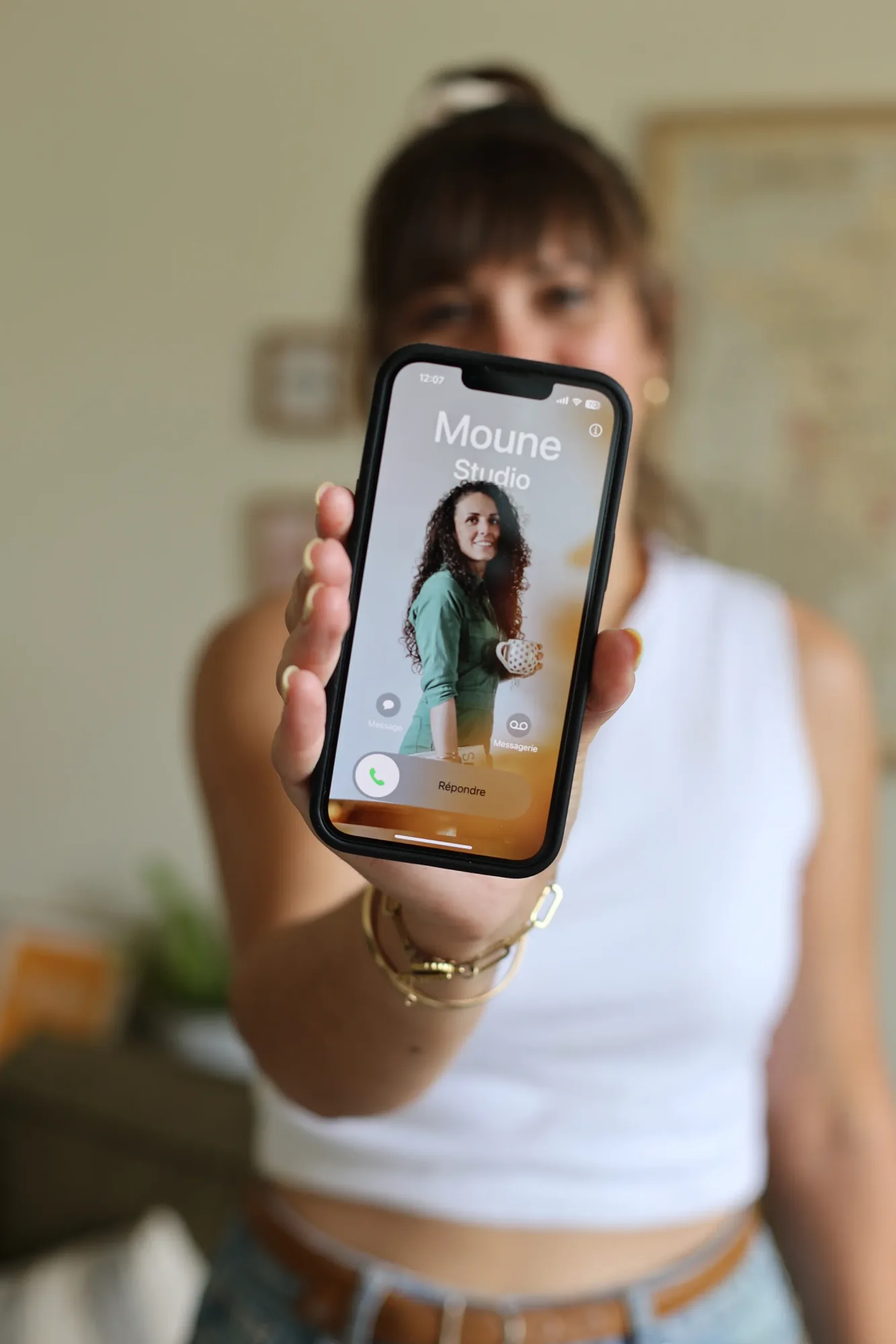 Un téléphone tendu vers l'objectif, un appel entrant de Moune Studio à l'écran